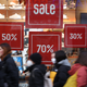 A photo of people walking past signs advertising a sale